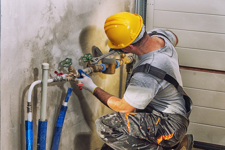 Plumber working at construction site on pipes wearing PPE