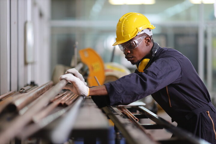 Worker handling pipe wearing PPE