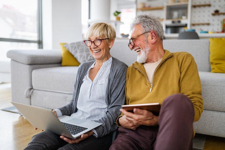 Older couple sitting on floor reading a book together