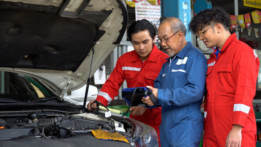 Three automotive mechanics working on car engine